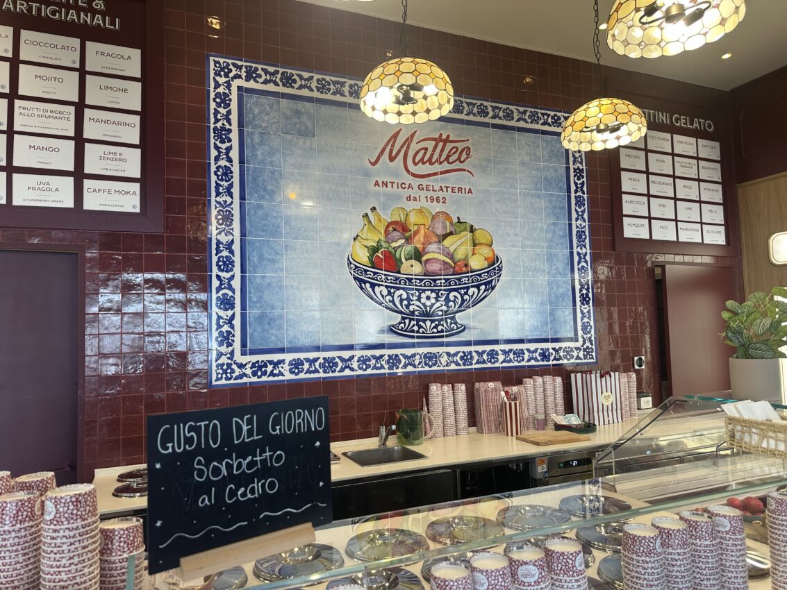 Interni di Antica Gelateria Matteo a Milano con piastrelle decorate, menu dei gusti e lavagna con sorbetto al cedro.