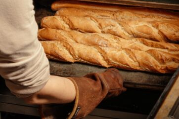Fornaio estrae baguette appena sfornate dal forno nel nuovo store Panfé di Corso Unione Sovietica a Torino.