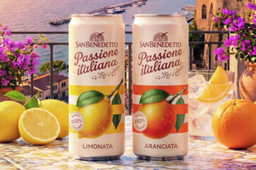 Lattine San Benedetto Passione Italiana, limonata e aranciata, con limoni e arance su tavolo in terrazza sul mare