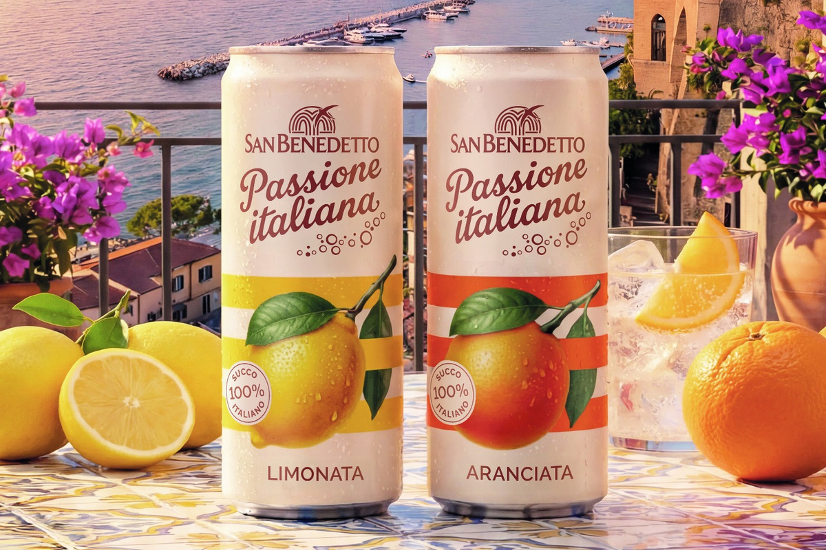 Lattine San Benedetto Passione Italiana, limonata e aranciata, con limoni e arance su tavolo in terrazza sul mare