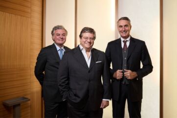 Manager di Compagnia del Gusto e Winelivery in posa per l'acquisizione, tre uomini in giacca e cravatta in ufficio.