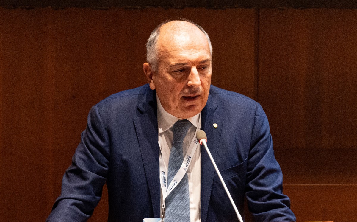 Uomo in giacca e cravatta parla al microfono durante un evento sulla ristorazione in catena.