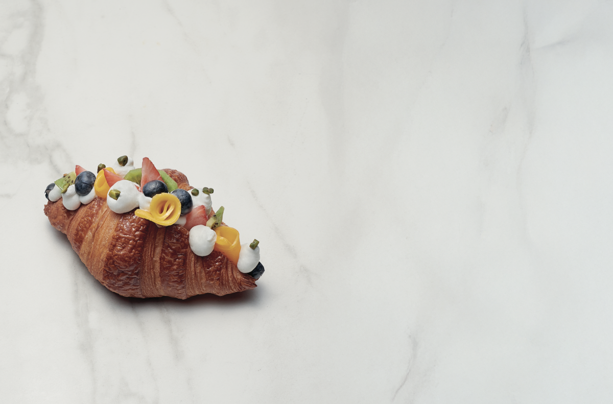 Croissant con macedonia di frutta fresca e panna. Colazione dolce e gustosa.