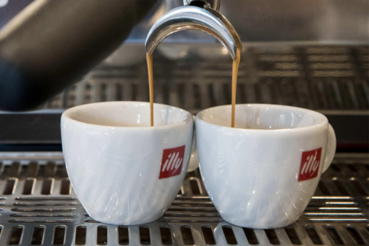Due tazze di caffè Illy vengono riempite da una macchina da espresso.