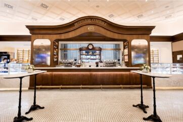 Bar Centrale Cova Milano. Design elegante con bancone in legno, tavolini in marmo e pavimento a mosaico.