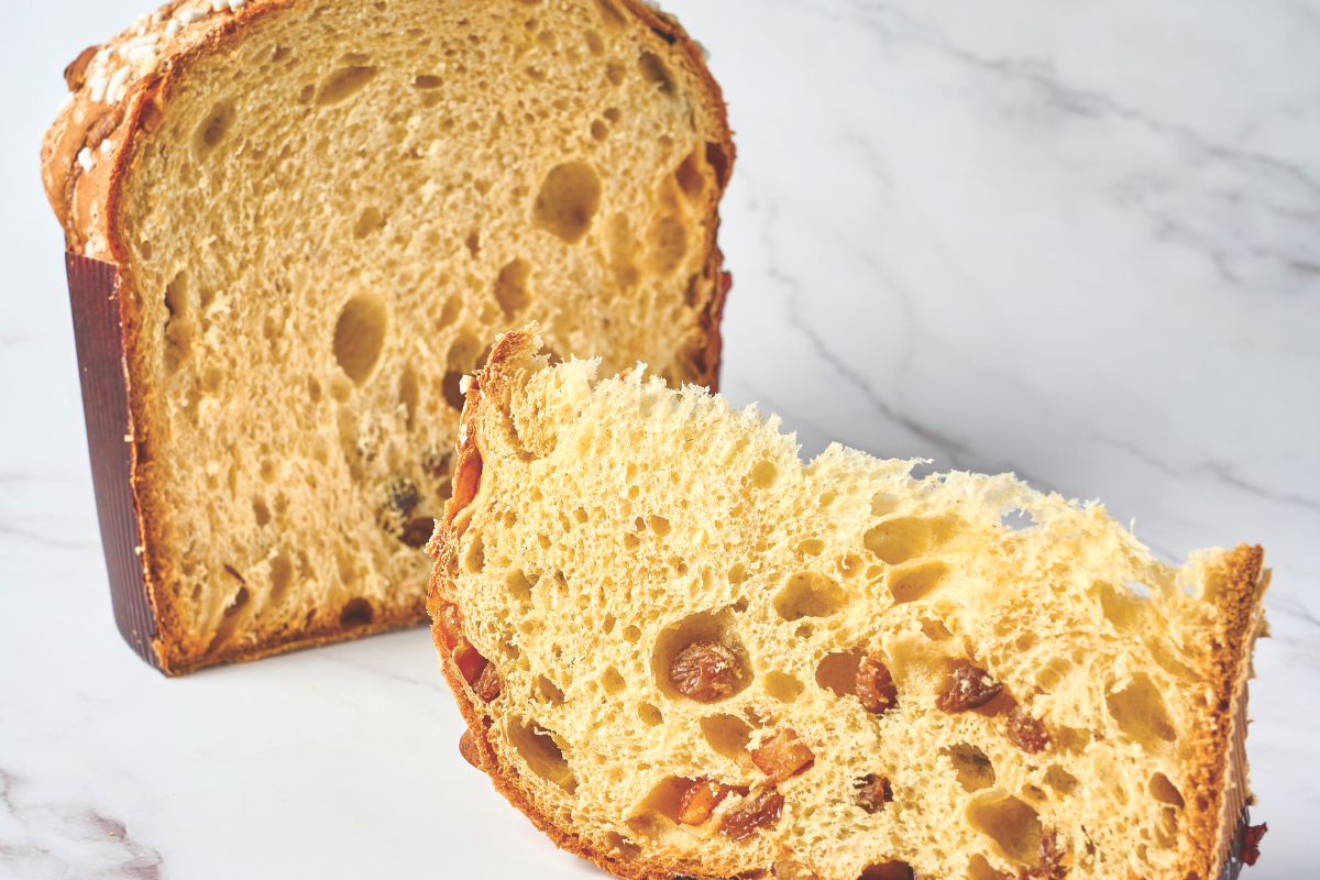 Fetta di panettone tradizionale con uvetta e canditi. Dolce natalizio artigianale.
