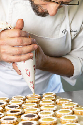 Chef decora biscotti con crema Irca da sac à poche. Pasticceria artigianale.