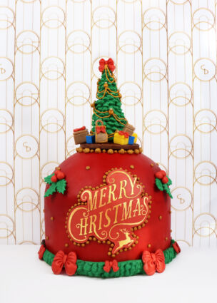 Torta artistica di Natale. Decorazioni rosse, albero di Natale e scritta Merry Christmas. Collezione Natale 2025.