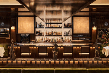 Interni eleganti del bar Sant Ambroeus Parigi. Bottiglie di liquore, sedie in pelle e sculture.