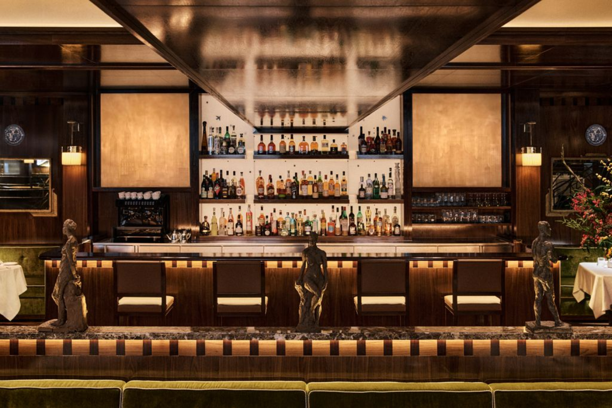 Interni eleganti del bar Sant Ambroeus Parigi. Bottiglie di liquore, sedie in pelle e sculture.