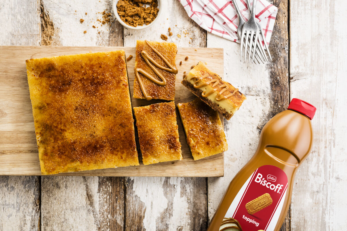 Cheesecake con topping Lotus Biscoff. Dessert cremoso con biscotti. Bottiglia di topping Biscoff.