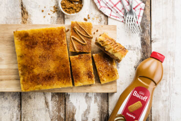 Cheesecake con topping Lotus Biscoff. Dessert cremoso con biscotti. Bottiglia di topping Biscoff.