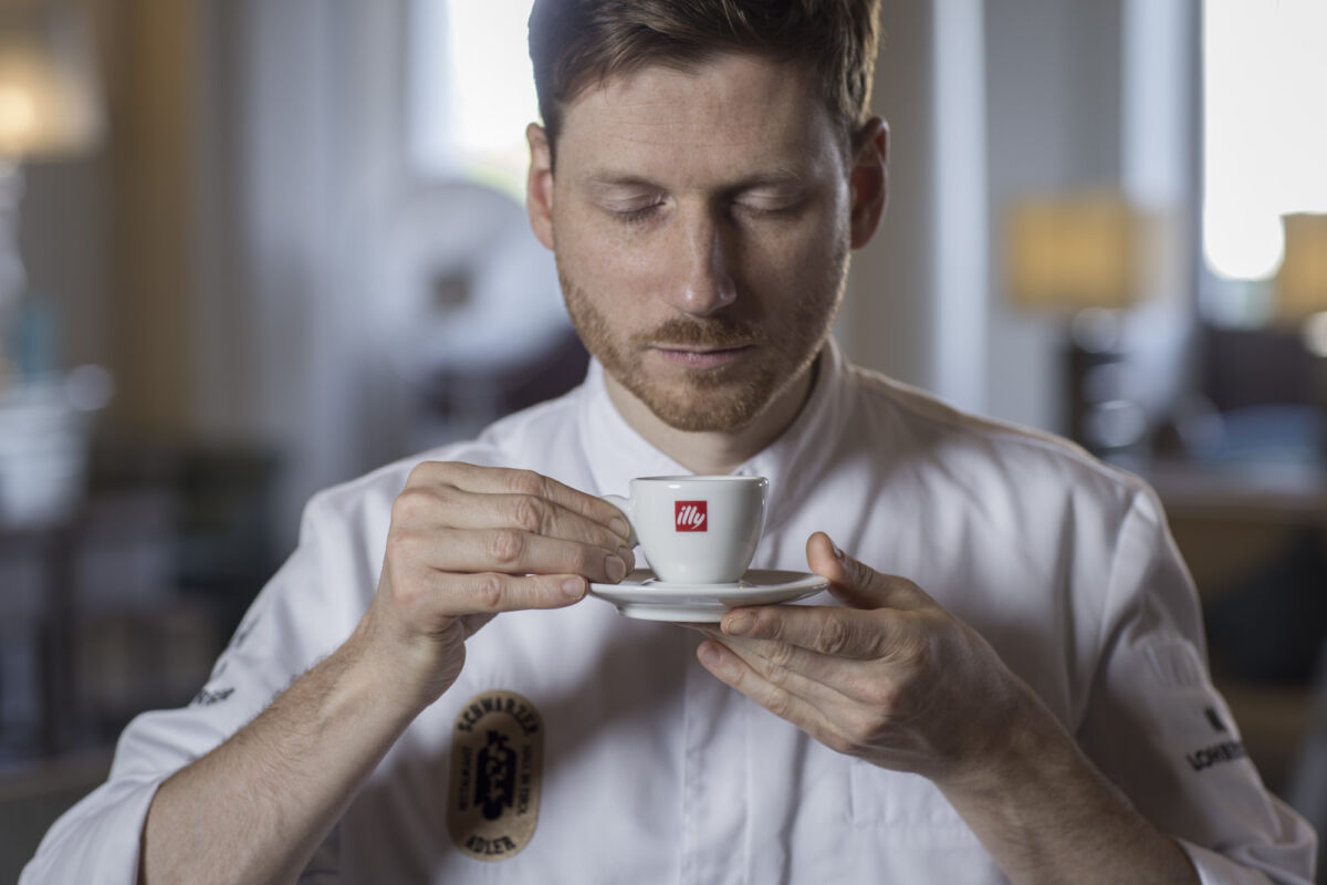 Uomo con tazza di caffè Illy. Degustazione caffè, aroma intenso.