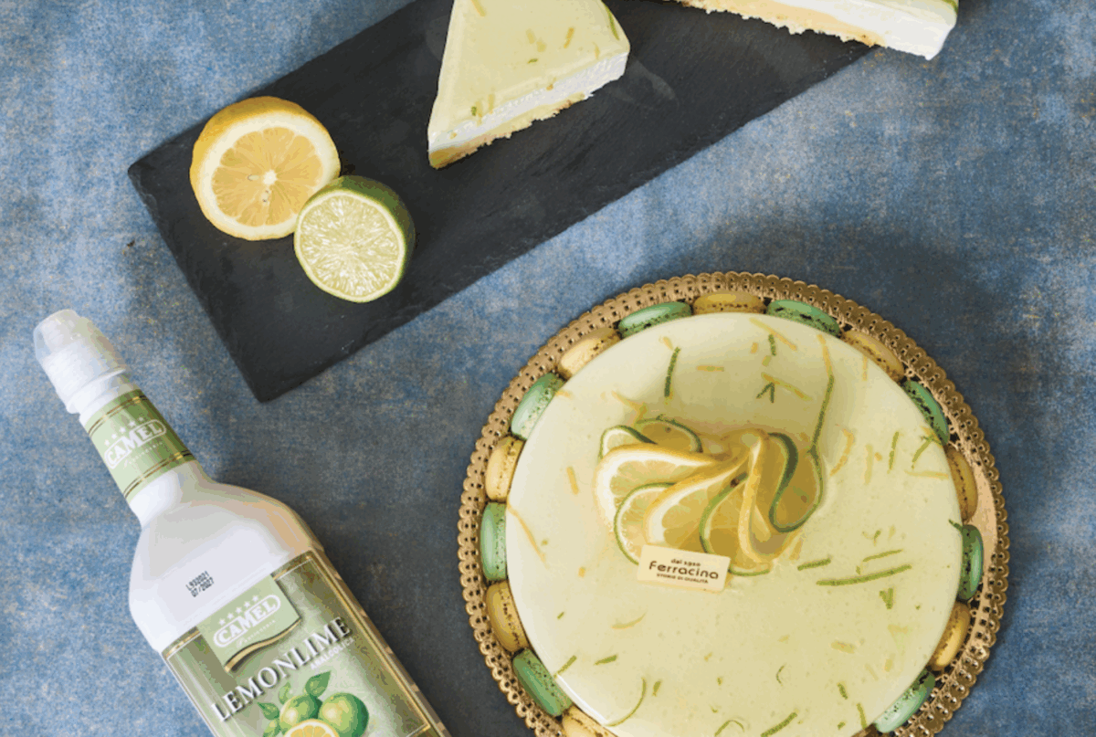 Dolce agli agrumi: torta al limone e lime, fetta di torta, bottiglia di limoncello. Dessert fresco e goloso.