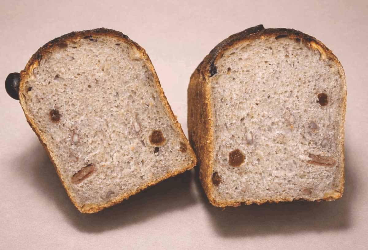 Sezioni di pane Nociatino artigianale. Pane con noci e uvetta, crosta dorata. Perfetto per colazione o snack.