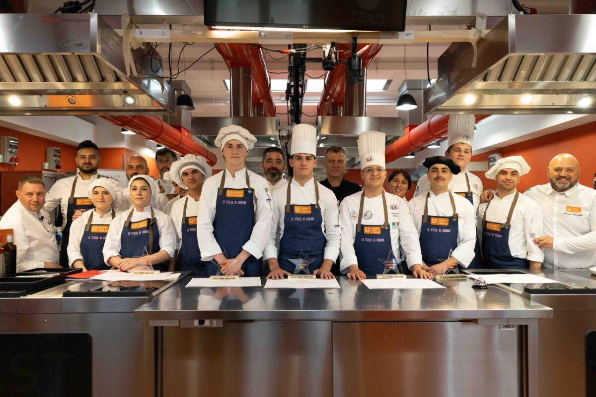 Team di cucina Le Stelle di Domani. Giovani chef italiani in posa con divise e cappelli da cuoco. Talento culinario.