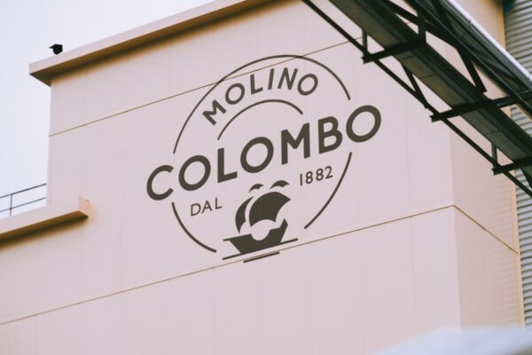 Facciata esterna dello stabilimento Molino Colombo con logo aziendale e scritta dal 1882, produzione di farina di qualità.