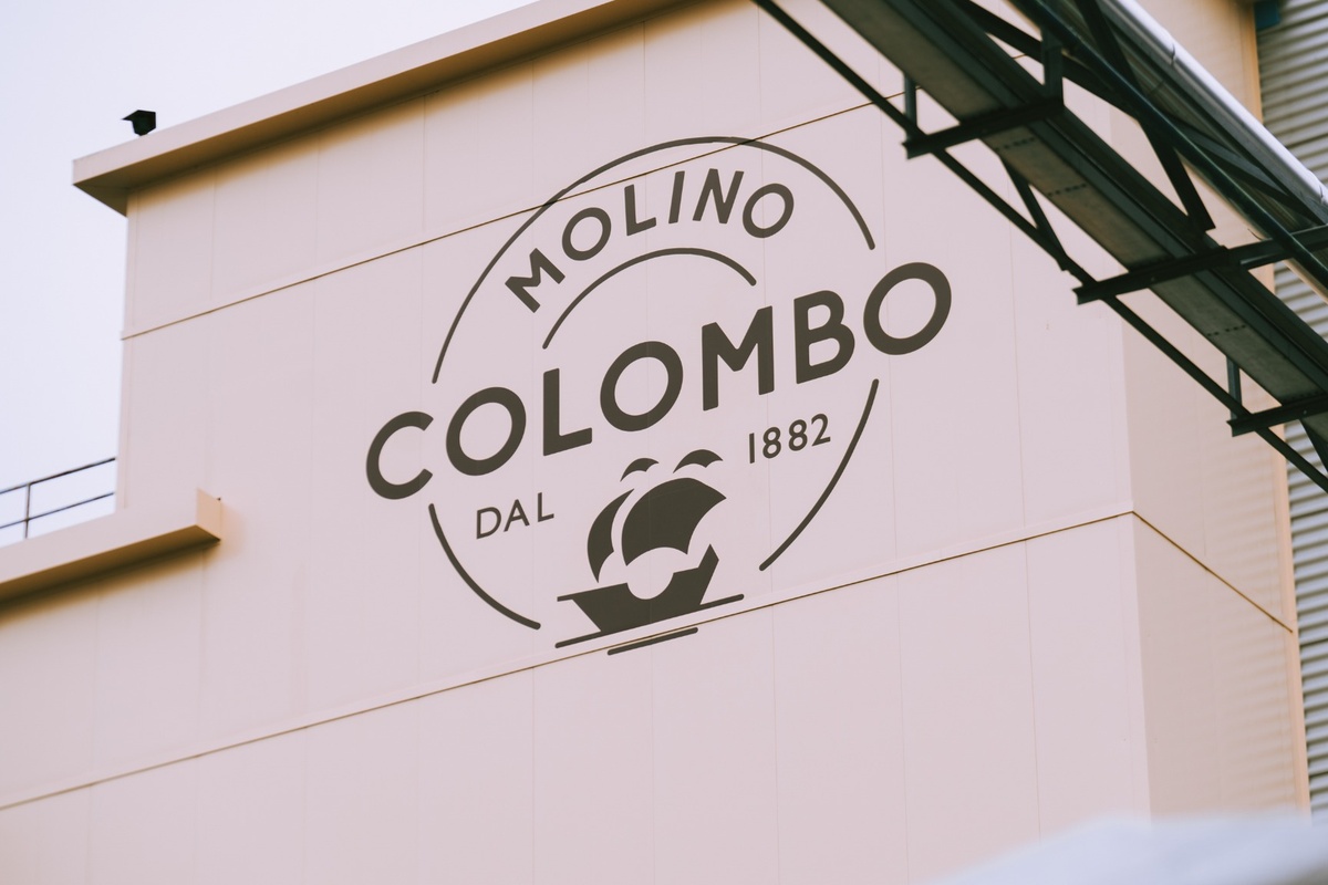 Facciata esterna dello stabilimento Molino Colombo con logo aziendale e scritta dal 1882, produzione di farina di qualità.