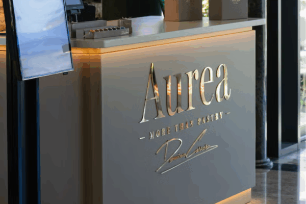 Bancone della pasticceria Aurea di Damiano Carrara con logo dorato in rilievo e scritta More Than Pastry.