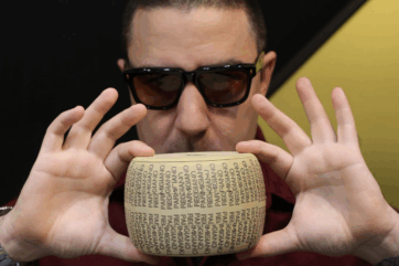 Fabrizio Fiorani tiene tra le mani una forma di Parmigiano Reggiano a Identità Golose per i suoi cremini al cacao.
