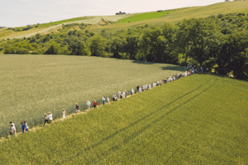 Lunga fila di persone cammina tra i campi di grano del Molino Paolo Mariani per l'evento 360 Grani dedicato all'Arte Bianca.