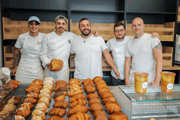 Il team di Sfoorna, micro forno artigianale di Carpe Diem a Pescara, sorridente davanti a pane e cornetti appena sfornati.