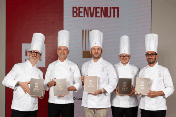 Cinque nuovi soci AMPI in divisa da pasticciere tengono in mano l'attestato ufficiale durante la cerimonia di premiazione.