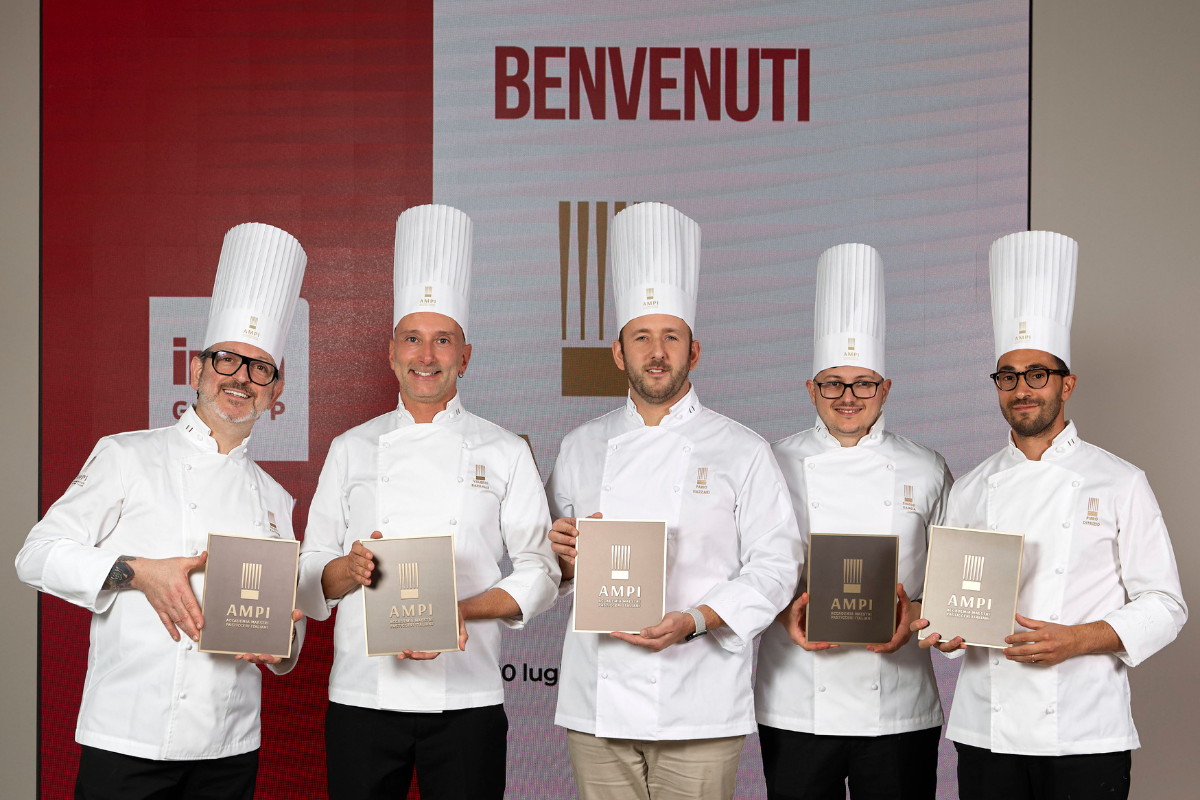 Cinque nuovi soci AMPI in divisa da pasticciere tengono in mano l'attestato ufficiale durante la cerimonia di premiazione.