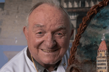 Ritratto del maestro pasticciere italiano Gastone Pegoraro sorridente accanto a una sua creazione artistica in zucchero.