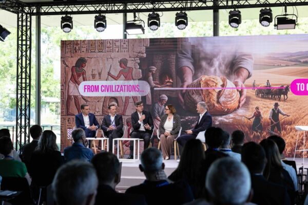 Panel di esperti al Lesaffre Symposium con sfondo storico sulla panificazione e il grano, pubblico in sala.