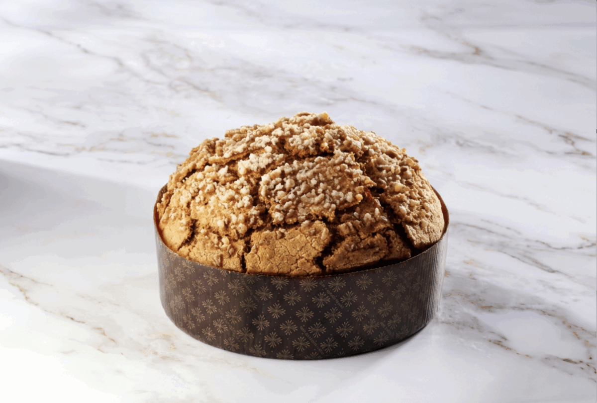 Panettone artigianale agli agrumi con croccante glassa in superficie, poggiato su un elegante piano in marmo bianco.