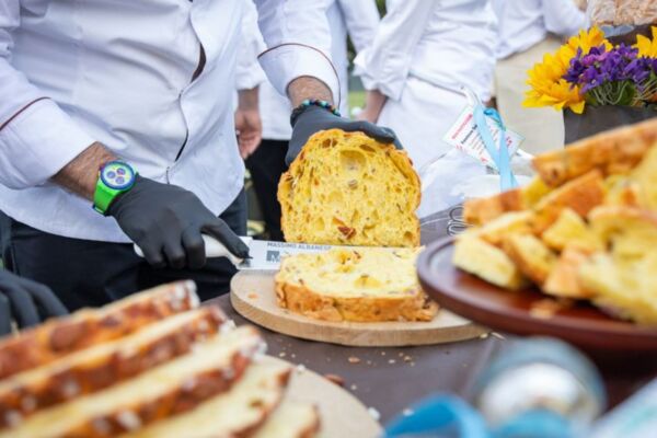 Pasticciere taglia un panettone artigianale a lievito madre durante la Notte dei Maestri del Lievito Madre a Parma.