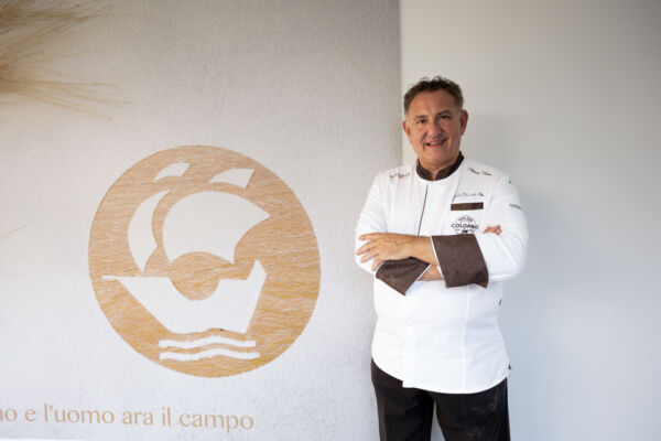 Il pasticciere Sal De Riso in tour presso Molino Colombo, sorridente con la sua giacca da chef professionale.