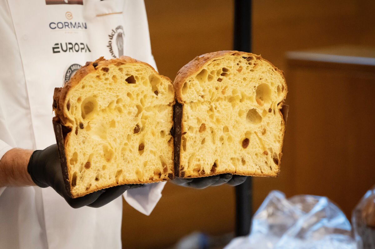 Panettone artigianale tagliato a metà, alveolatura soffice e canditi visibili, tenuto da un pasticcere.