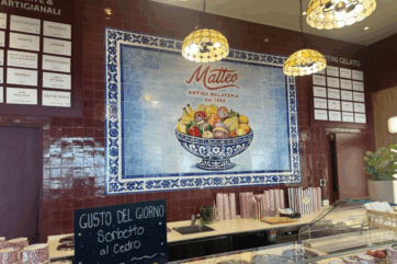 Interni di Antica Gelateria Matteo a Milano con decorazioni in ceramica, fruttini gelato e listino gusti artigianali.