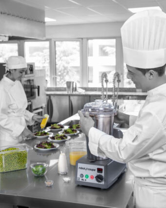 Chef usa frullatore professionale Robot Coupe in cucina, preparazione piatti gourmet con verdure fresche