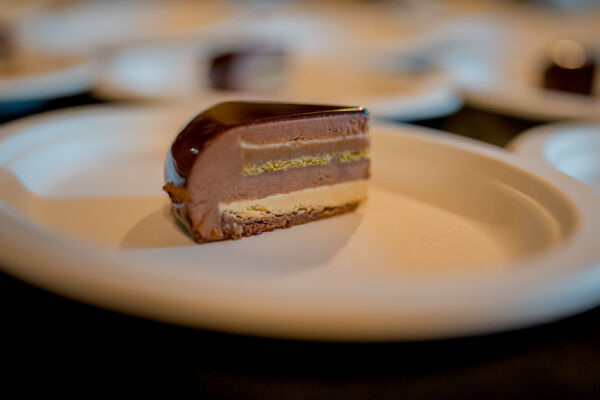 Fetta di torta dessert couture di Giuseppe Manilia con glassa al cioccolato su piatto bianco in passerella