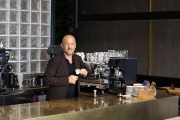 Francesco Sanapo, fondatore di Ditta Artigianale, al bancone del nuovo caffè di Via Capelli a Milano con tazzina in mano.