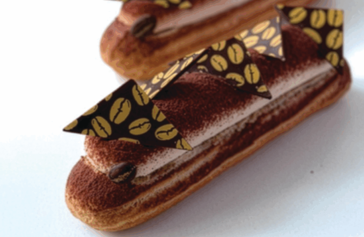 Eclair tiramisù con crema al mascarpone, spolverato di cacao e decorato con cialde a forma di chicchi di caffè