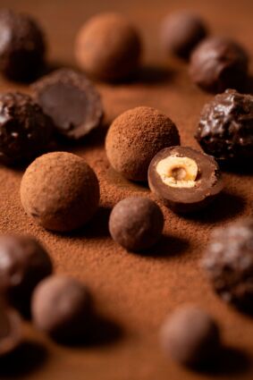 Praline al cioccolato Da Vittorio con granella e cuore alla nocciola su sfondo cocoa