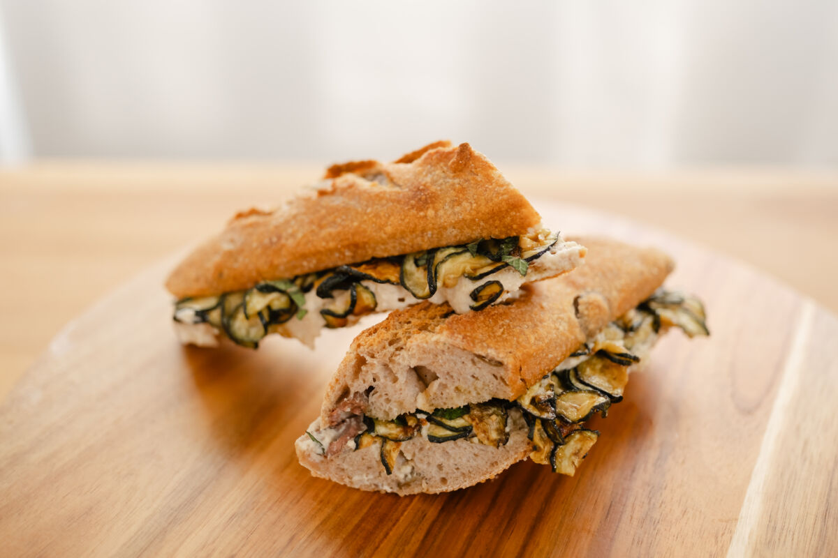 Filoncini grano duro farciti con zucchine grigliate e formaggio su tagliere di legno