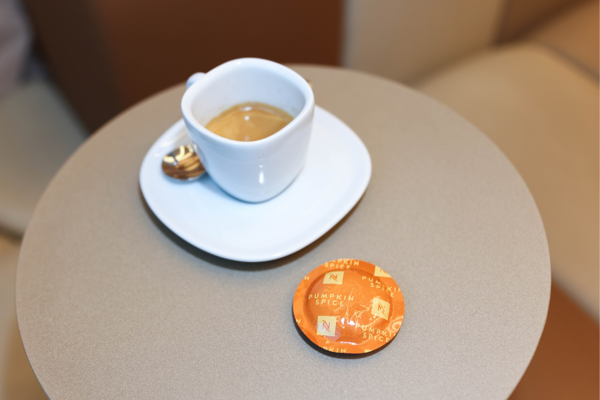 Tazzina Nespresso con caffè su tavolo bakery e capsula arancione: caffè out of home