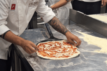 Pizzaiolo stende pizza milanese contemporanea con Molino Pasini, farina e mozzarella in cucina.