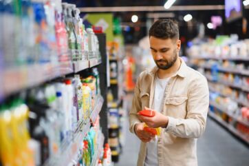 Uomo al supermercato. Cura della casa e pulizia, scaffali con detersivi.