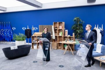 Bioeconomia in Europa: relatori a podio, bandiere UE, prodotti eco-friendly in esposizione. Innovazione e sostenibilità.