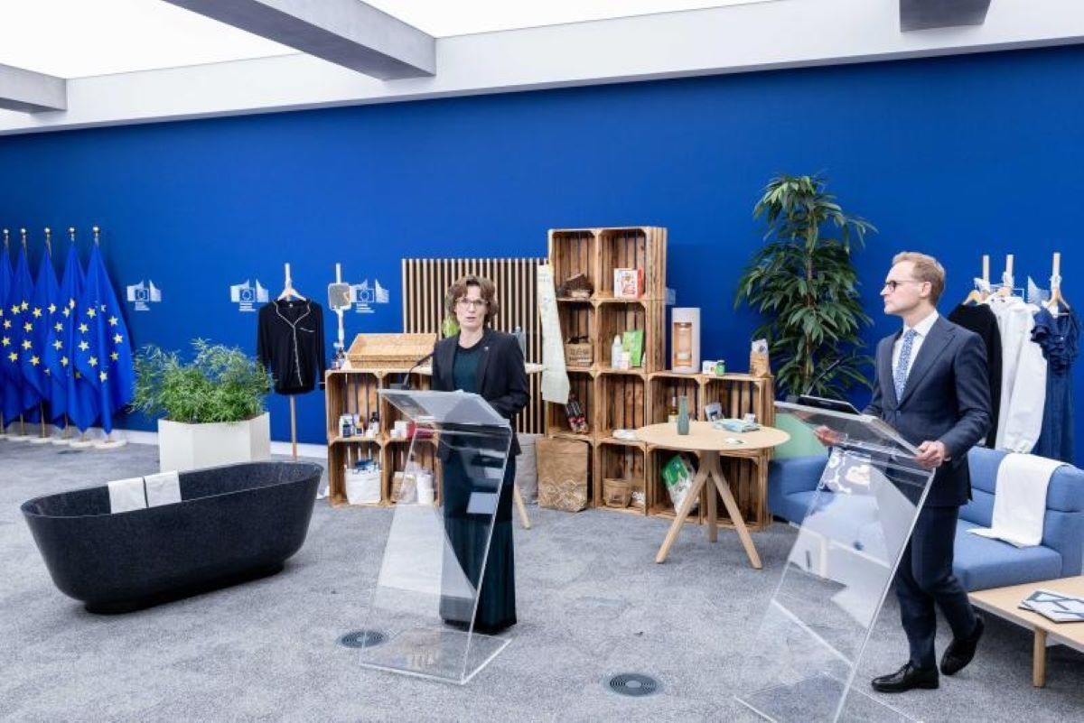 Bioeconomia in Europa: relatori a podio, bandiere UE, prodotti eco-friendly in esposizione. Innovazione e sostenibilità.