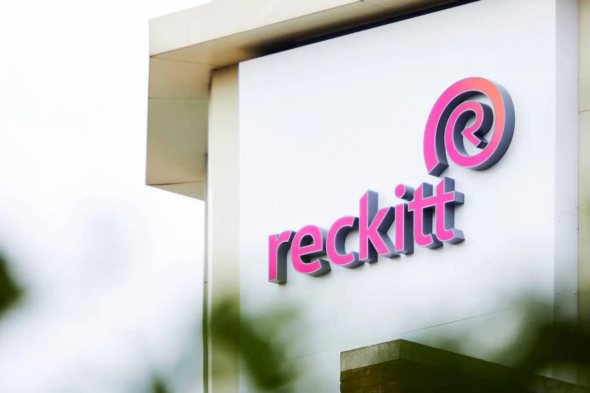 Logo Reckitt in rosa e grigio su edificio bianco. Reckitt cede Essential Home ad Advent International.