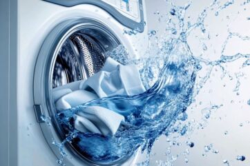 Lavatrice con bucato e spruzzi d'acqua. Detersivi per lavatrice efficaci.
