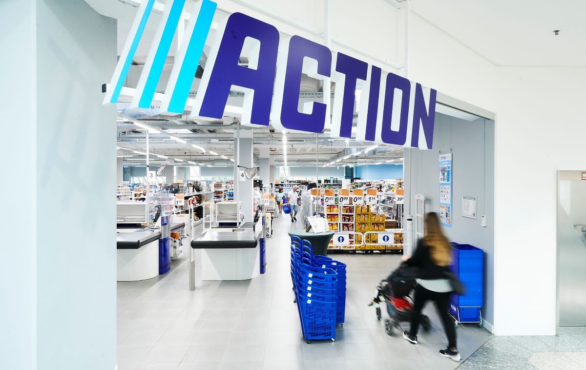 Ingresso negozio Action in Italia. Corsie e casse con clienti. Action, la corsa allo shopping continua.