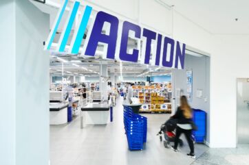Punto vendita Action. Ingresso negozio Action con cliente e carrello. Vendite Action in crescita.
